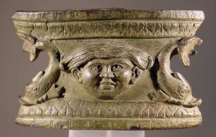 Basis mit Reliefschmuck: Maske zwischen Delphinen