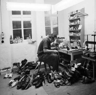 Schuhmacher : Wurzen. Ein Schuhmacher bei der Arbeit, an seinem Arbeitsplatz in seiner Werkstatt, umringt von Werkzeug und Schuhen