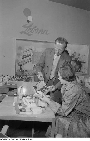 Verkäufer führt Kundin Produkte der Lebona Parfümerie vor, Herbstmesse 1953