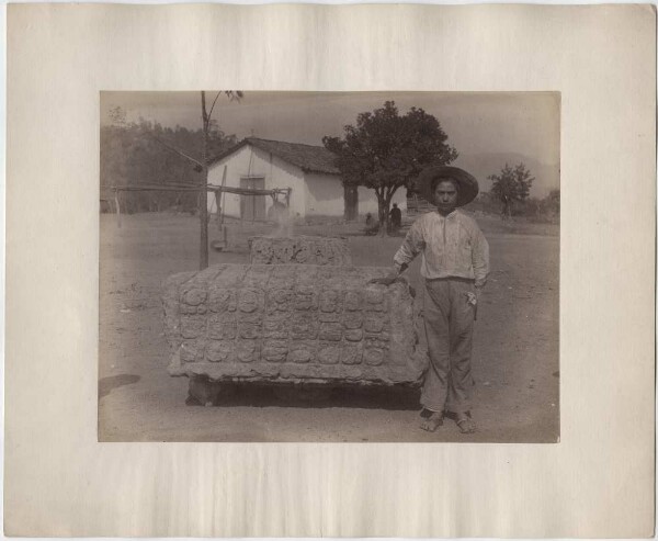 Altar U, east side. Local boy standing next to it, village in the background.