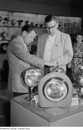 Besucher der Leipziger Herbstmesse 1954 betrachten Scheinwerfer