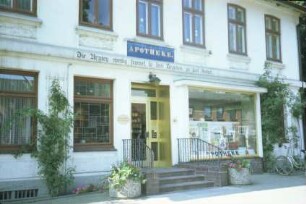 Kirchenstraße 44: Apotheke: traufständige Straßenfront: Teilansicht: Eingangstür, Schaufenster, Gesims mit Sinnspruch: Eingangstreppe