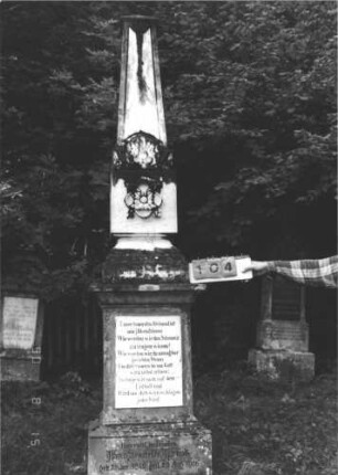 Grabstein 104 (Index: 100106447) Material: Marmor, Sockel Sandstein Zustand: Platte einzementiert Maße HxBxT: 317x63x45 cm Beschreibung: Obelisk, in der Mitte eingezogen, profilierter, getreppter Sockel, auf dem Sockel rechteckige Schrifplatte Symbolik: floral: Grabstein 104