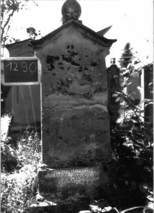 Grabstein 1290 (Index: 100104543) Material: Sandstein Zustand: Stele in der Mitte durchgebrochen, repariert, vollständig verwittert Maße HxBxT: 160x46x12 cm Beschreibung: Stele auf getrepptem Sockel, giebelartiger Abschluss mit Giebelakroter (Palmette), unterhalb des Giebels seitliche Auskragungen: Grabstein 1290