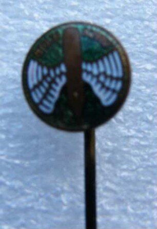 Verbandsabzeichen Stolze-Schrey (mit langer Nadel) : Sammlung Beinhorn. Verbandsabzeichen Stolze-Schrey (geflügelte Feder auf grünem Grund, mit langer Nadel). Email, Metall; Durchmesser 10 mm (nach 1897). Dresden: SLUB R c 0240