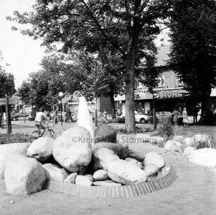 Rathausvorplatz [späterer Europaplatz]: Springbrunnen aus Findlingen: dahinter Poststraße mit Geschäften und Fußgängern