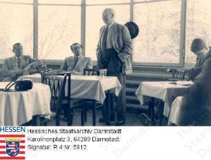 Bergsträsser, Ludwig, Prof. Dr. phil. (1883-1960) / Gruppenaufnahme in Raum im Bundeshaus von Bonn / Bergsträsser stehend, einen Vortrag haltend, Ganzfigur
