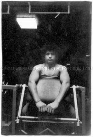 Bodybilder sitzt an einem Fitnessgerät (Prämiertes Foto Altersgruppe 18-21)