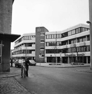 Kreissparkasse Stormarn: Hagenstraße: Zentrale: vor Einweihung, mit Firmenname: im selben Gebäude links Buchhandlung Spethmann: davor parkende Autos: Vorplatz mit jungen Bäumen, runden Sitzbänken, Straßenschilder, Straßenlampen: links Eckhaus Altbau Kreissparkasse an Markt: Jugendliche