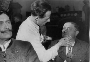 In Vorbereitung von Filmaufnahmen schminckt ein Maskenbilder der Ufa Schauspieler. Aufgenommen 1938