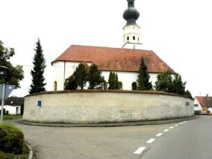 Ansicht von Norden mit Kirche (im Kern-14-15 Jh) über Kirchhofmauer (Steinbrüstung des Wehrgangs mit Schießscharten im 18 Jh glatt verputzt) von Ortsseite