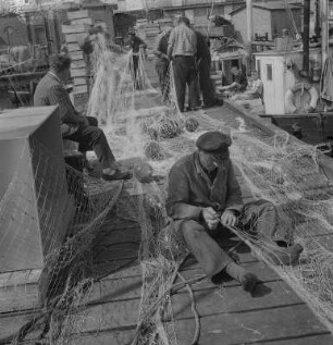 Saßnitz. Fischereihafen, beim Netzeflicken