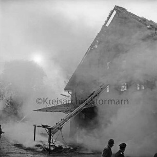 Gut Altfresenburg: Brand des Bullenstalls: Brandruine: Giebelfront mit Lastenaufzug: vorn rechts Feuerwehrmann und Mann: hinten Rauchschwaden: 24. August 1971