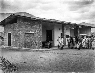 Bungalow in Makania : Vermutlich Arbeiter vor einem Bungalow in Makania.