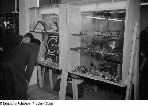 Fachbesucher vor Vitrinen mit Brillengläsern der Firma Carl Zeiss Jena