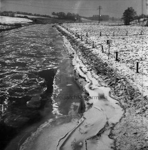 Trave: eingebrochene Eisdecke bei Niedrigwasser: rechts Wiesen und Zäune: hinten Knicklandschaft: Winter