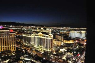 Nächtliches Las Vegas mit Caesars Palace Hotel : Blick vom Nachbau des Pariser Eiffelturms am Las Vegas Boulevard auf das am Abend beleuchtete Las Vegas, aufgenommen am 8. August 2012