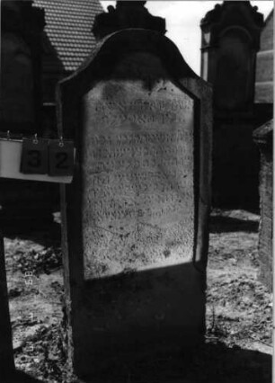 Grabstein 32 (Index: 99797933) Material: Sandstein, weiß Zustand: stark verwittert Maße HxBxT: 129x62x11 cm Beschreibung: Stele, geschweifter Abschluß: Grabstein 32 (Detailaufnahme)