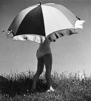 Frau im Badeanzug unter einem großen Sonnenschirm