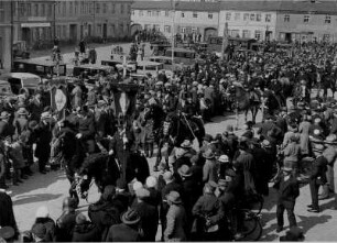 Osterreiten in der Oberlausitz. Die Ostereiter versammeln sich auf dem Marktplatz. Sie reiten dann zur Pfarrkirche in das Dorf Ralbitz. An der Spitze der Reitergruppe befinden sich die Fahnenträger. Das Osterreiten findet breites Interesse. Auf dem Marktplatz schauen zahlreiche Besucher zu