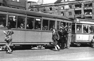 Berlin. Straßenbahn der Linie 77 mit Hänger (Nummer 110) in einem Haltestellenbereich. Fahrgäste beim Einsteigen