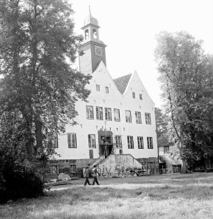 Herrenhaus: Restaurierungsarbeiten an Nordportal und Treppe: davor Baumaterial: links zwei Männer auf Auffahrt: vorn Rasenfläche: rechts und links Bäume