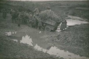 Zweiter Weltkrieg. Sowjetunion. Kampfpausen. Einheimische und Soldaten schieben einen Heuwagen durch eine schlammige Furt