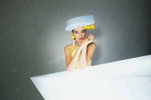 Model in Schaumstoffmode : Model mit Schaumstoffhut und -kostüm hinter einem Neonleuchtkörper