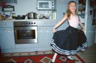 Kleine Schwester posiert im Ballettkleid in der Küche (Altersgruppe bis 14)