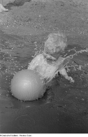 Kleines Kind, mit einem Ball im Wasser spielend