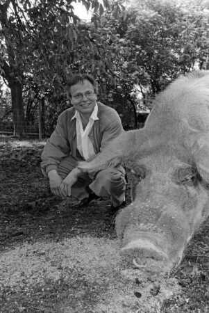 Hof von Günther Fielmann: Besitzer hockend bei der Fütterung von Schwein Borsti