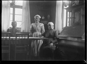 Pflegerin mit Patientinnen am Tisch im Zimmer