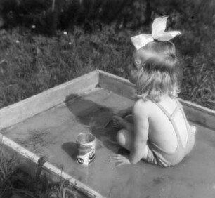 Kinderbilder. Kleines Mädchen, in einem flachen Planschbecken sitzend