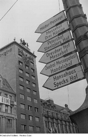 Hinweisschilder zu den Messehäusern an einem Lichtmast vor dem Kroch-Hochhaus