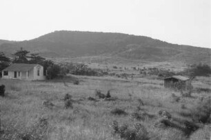 Landschaft : Blick über ein Gehöft auf einen angrenzenden Hügel.