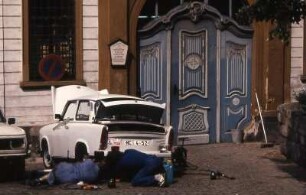 Trabantreparatur auf der Straße : Zwei Männer liegen auf der Straße und reparieren einen Trabant. Aufgenommen im Frühjahr 1990 in Gera