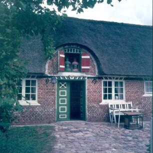 Dänemark. Nordseeinsel Fanø. Reetgedecktes Fischerhaus mit Dekoration im Dachfenster. Eingangsseite