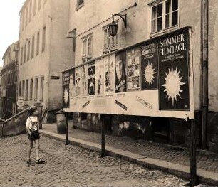 Sommerfilmtage in Colditz : Colditz. Ein kleiner Junge in Latzhosen läuft an einer Plakatwand vorbei und sieht sich die Filmwerbung auf den Plakaten an, die in den Sommerfilmtagen gespielt werden