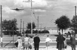 Berlin. Berliner Luftbrücke. Flugzeug (sogenannter Rosinenbomber) im Landeanflug. Ansicht mit wartenden Passanten