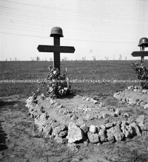 Soldatengrab mit Holzkreuz und Stahlhelm