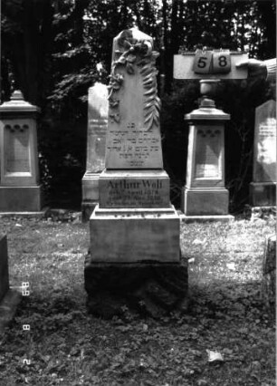 Grabstein 58 (Index: 100101496) Material: Marmor, unterster Sockelteil Kalkstein Zustand: gut Maße HxBxT: 153x35x28 cm Beschreibung: Obelisk, getreppter Sockel, unterster Sockelteil rusticaartig Symbolik: Palm- und Efeuzweig mit Blüten Steinmetz: Fugazza: Grabstein 58