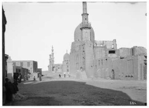 Kairo (Ägypten). Straßenszene mit Einheimischen vor der Ruine einer Moschee