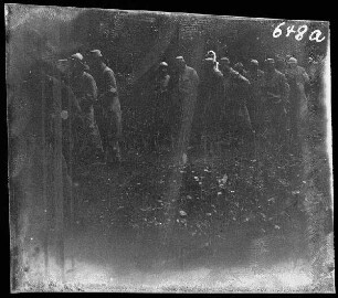 bei Neuville (=Neuville-Saint-Vaast, Dep. Pas-de-Calais, Frankreich): Gruppe von Soldaten (französische Kriegsgefangene?) am Wegesrand vor einem Backsteingebäude