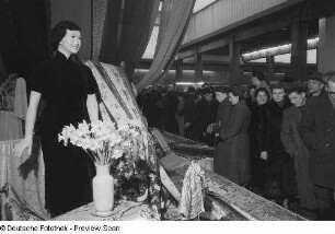 Besucher vor einem Messestand mit Stoffen im Ausstellungspavillon von China