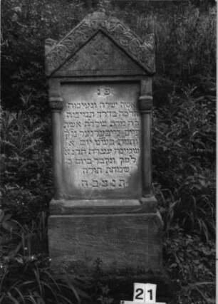 Grabstein 21 (Index: 100079849) Material: Sandstein Zustand: beschädigt, Sockel verwittert mit Textverlust Maße HxBxT: 151x57x26 cm Beschreibung: ädikulaartige Stele mit Halbsäulen, getreppter Sockel, Giebel mit Eckakroteren, rechteckiges Schriftfeld eingetieft Symbolik: Blätter, Ranken: Grabstein 21