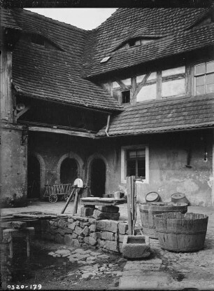 Hof eines Gehöfts mit Zubern und Schleifstein