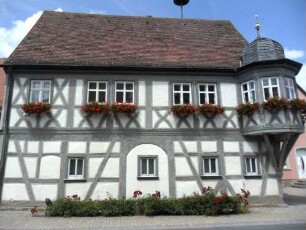 Rathaus (erbaut 1666)-Ansicht über Traufseite in Fachwerk-Riegelbauweise (einst offene Erdgeschoßhalle) und Eckerker im Obergeschoß auf Knaggen in Übersicht
