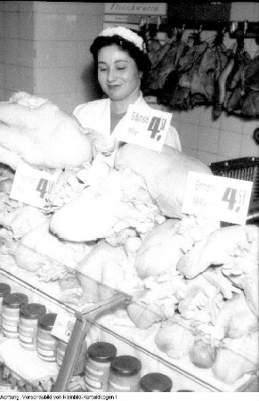 Dresden. Konsum, Verkaufsstelle. Verkäuferin hinter einer Kühltheke mit Geflügel, Dezember? 1956