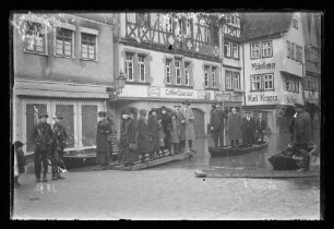 Hochwasser in der Brückengasse vor Cafe Quenzer und Möbellager Karl Kappes, Personen auf Schelchen, darauf Nr. 81