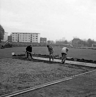 Stadion am Wendum: Erneuerung des Rasenplatzes: die städtische Gartenbaukolonne trägt den Rasen ab, im Hintergrund Wohngebäude